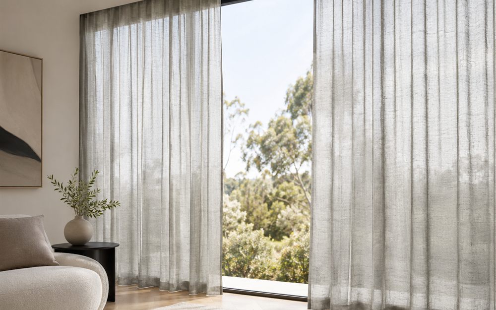 Sheer curtains framing a full-height window in a light-filled room