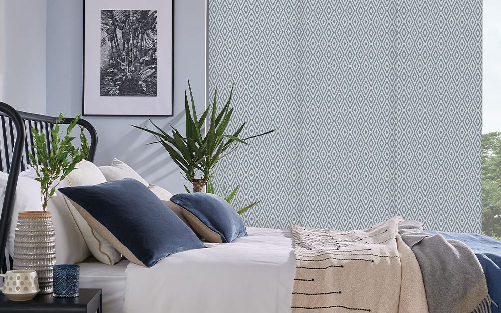 Wide fabric panel blinds sliding across a bedroom window wall